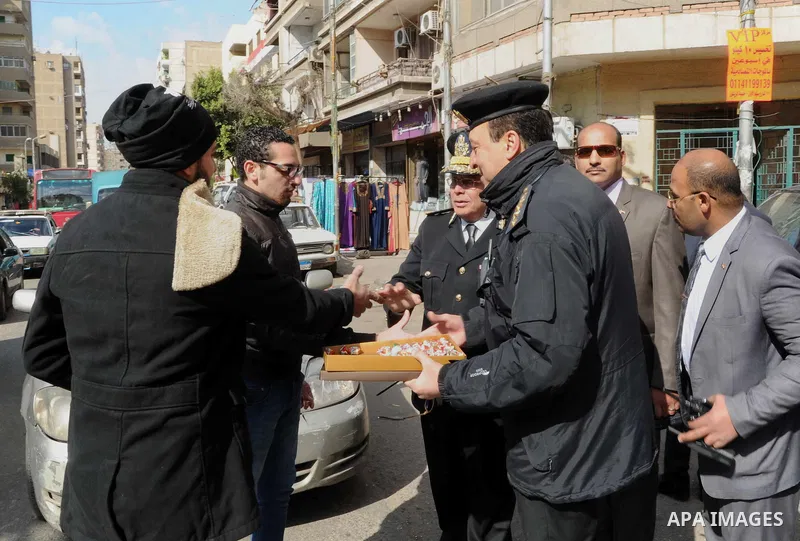 Egyptian policemen give out chocolates to citizens on Cairo's landmark Tahrir Square on January 25, 2016, as the country marks the fifth anniversary of the 2011 uprising. Egyptians marked the fifth anniversary of the upr...