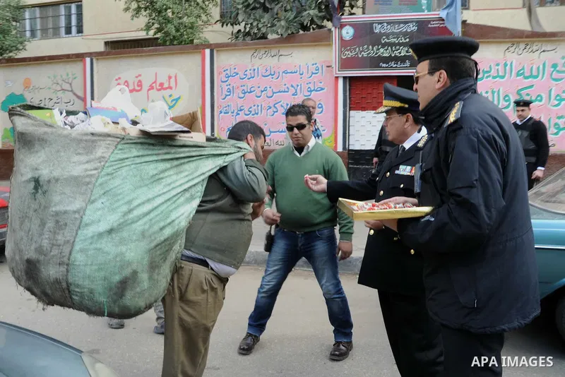 Egyptian policemen give out chocolates to citizens on Cairo's landmark Tahrir Square on January 25, 2016, as the country marks the fifth anniversary of the 2011 uprising. Egyptians marked the fifth anniversary of the upr...