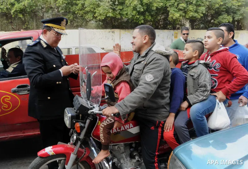 Egyptian policemen give out chocolates to citizens on Cairo's landmark Tahrir Square on January 25, 2016, as the country marks the fifth anniversary of the 2011 uprising. Egyptians marked the fifth anniversary of the upr...
