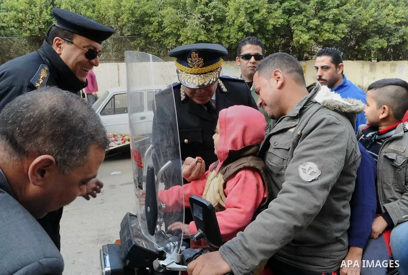 Egyptian policemen give out chocolates to citizens on Cairo's landmark Tahrir Square on January 25, 2016, as the country marks the fifth anniversary of the 2011 uprising. Egyptians marked the fifth anniversary of the upr...