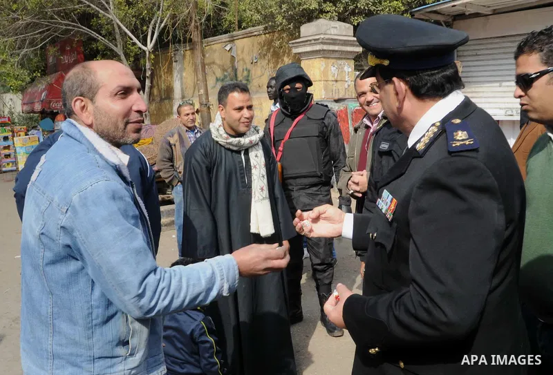 Egyptian policemen give out chocolates to citizens on Cairo's landmark Tahrir Square on January 25, 2016, as the country marks the fifth anniversary of the 2011 uprising. Egyptians marked the fifth anniversary of the upr...