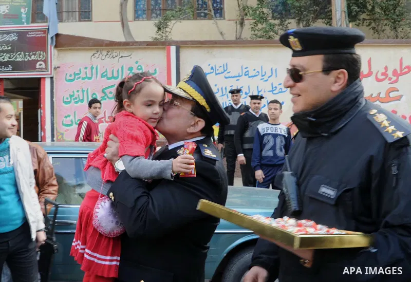 Egyptian policemen give out chocolates to citizens on Cairo's landmark Tahrir Square on January 25, 2016, as the country marks the fifth anniversary of the 2011 uprising. Egyptians marked the fifth anniversary of the upr...