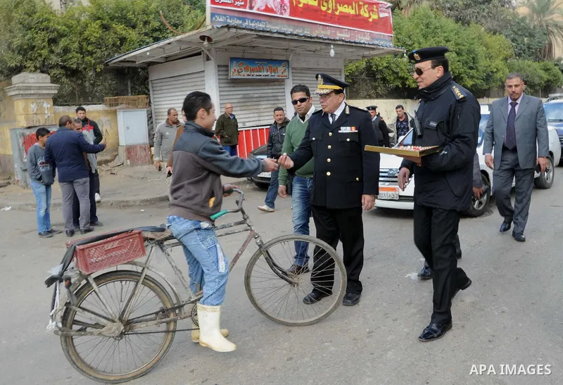Egyptian policemen give out chocolates to citizens on Cairo's landmark Tahrir Square on January 25, 2016, as the country marks the fifth anniversary of the 2011 uprising. Egyptians marked the fifth anniversary of the upr...