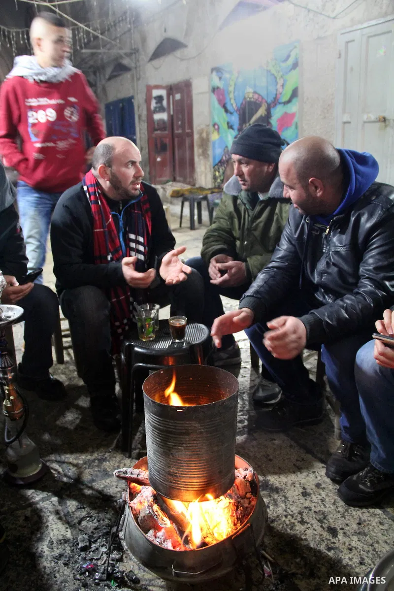 Palestinians warm themselves next to a fire on a rainy day in Jerusalem's Old city, on Jan. 25, 2016. Photo by Mahfouz Abu Turk