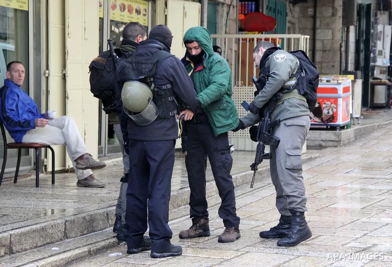 Israeli policemen detains a Palestinian man on a rainy day in Jerusalem's Old city, on Jan. 25, 2016. Photo by Mahfouz Abu Turk