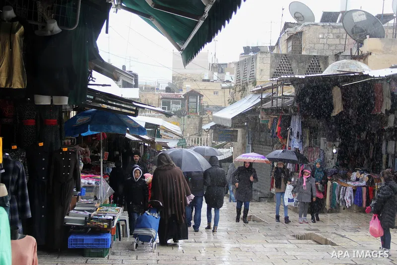 Palestinians walk at a street on a rainy day in Jerusalem's Old city, on Jan. 25, 2016. Photo by Mahfouz Abu Turk