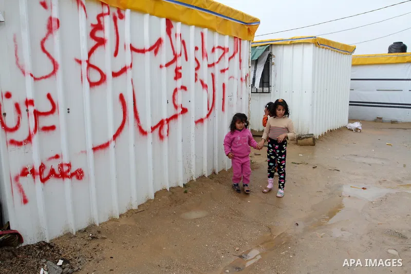 Palestinian children walk past temporary housing during a winter storm in the southern Gaza Strip town of Khan Younis on January 25, 2016. Photo by Abed Rahim Khatib