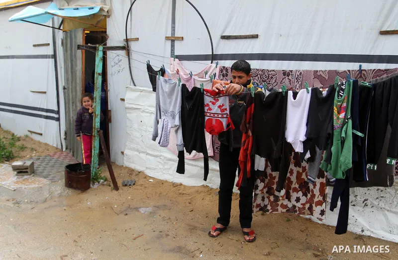 A Palestinian boy hangs laundry outside his temporary housing during a winter storm in the southern Gaza Strip town of Khan Younis on January 25, 2016. Photo by Abed Rahim Khatib