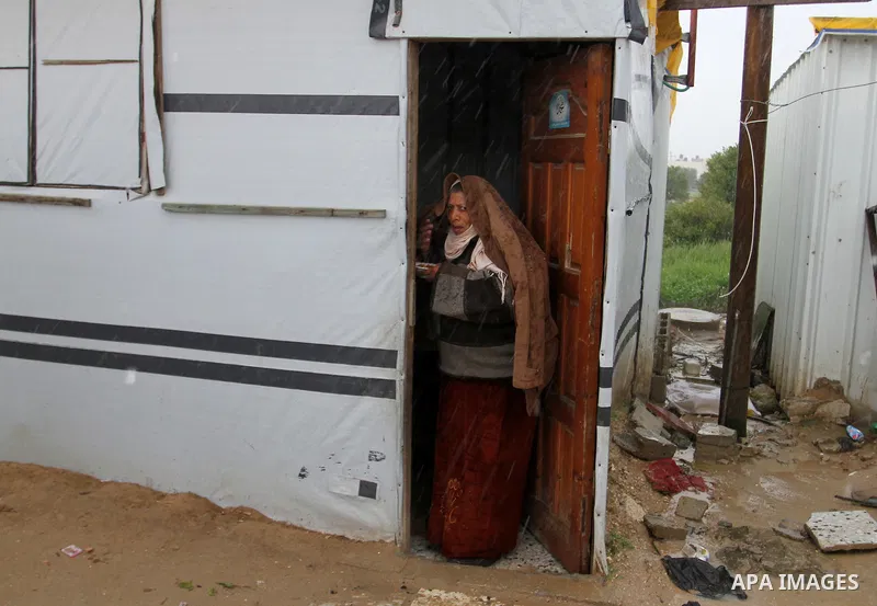 A Palestinian woman peaks from inside her temporary housing during a winter storm in the southern Gaza Strip town of Khan Younis on January 25, 2016. Photo by Abed Rahim Khatib