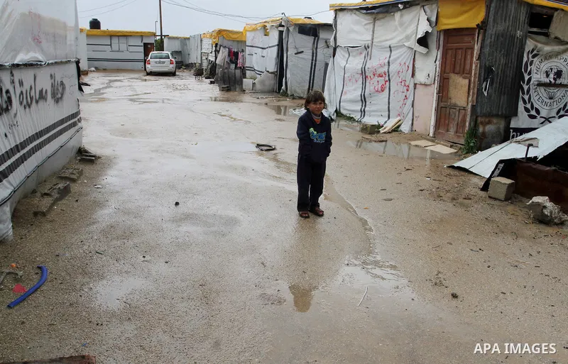 A Palestinian child walks past temporary housing during a winter storm in the southern Gaza Strip town of Khan Younis on January 25, 2016. Photo by Abed Rahim Khatib