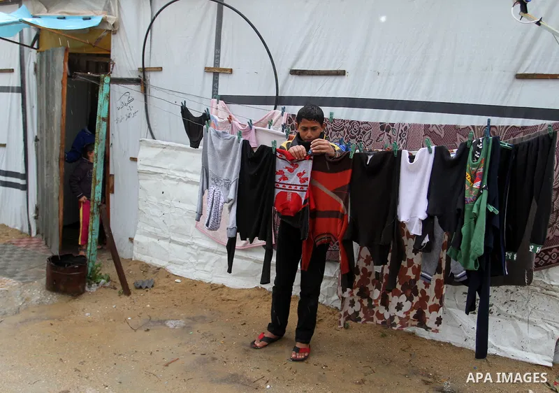 A Palestinian boy hangs laundry outside his temporary housing during a winter storm in the southern Gaza Strip town of Khan Younis on January 25, 2016. Photo by Abed Rahim Khatib