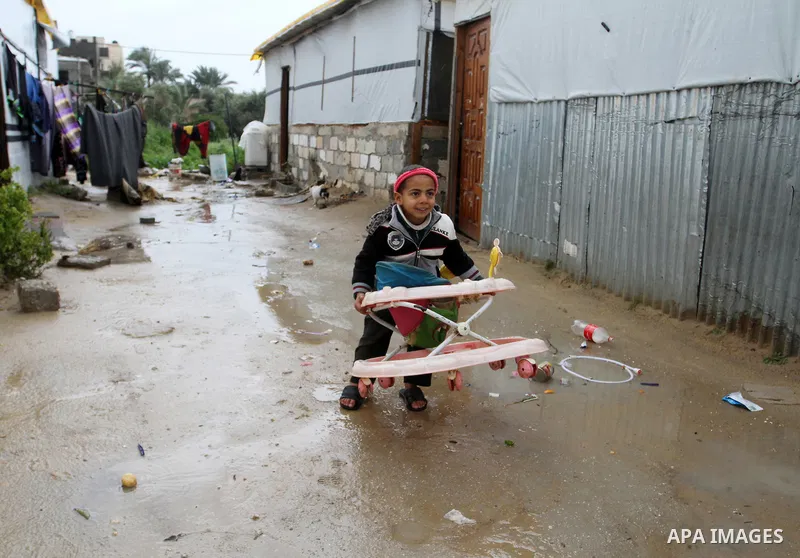 A Palestinian child walks past temporary housing during a winter storm in the southern Gaza Strip town of Khan Younis on January 25, 2016. Photo by Abed Rahim Khatib