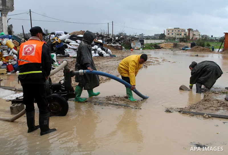 Members of Palestinian Civil Defence work in a flooded street with sewage during a winter storm in the southern Gaza Strip town of Khan Younis on January 25, 2016. Photo by Abed Rahim Khatib