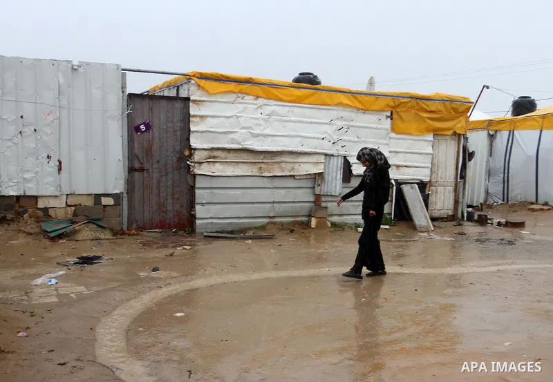 A Palestinian woman walks past temporary housing during a winter storm in the southern Gaza Strip town of Khan Younis on January 25, 2016. Photo by Abed Rahim Khatib