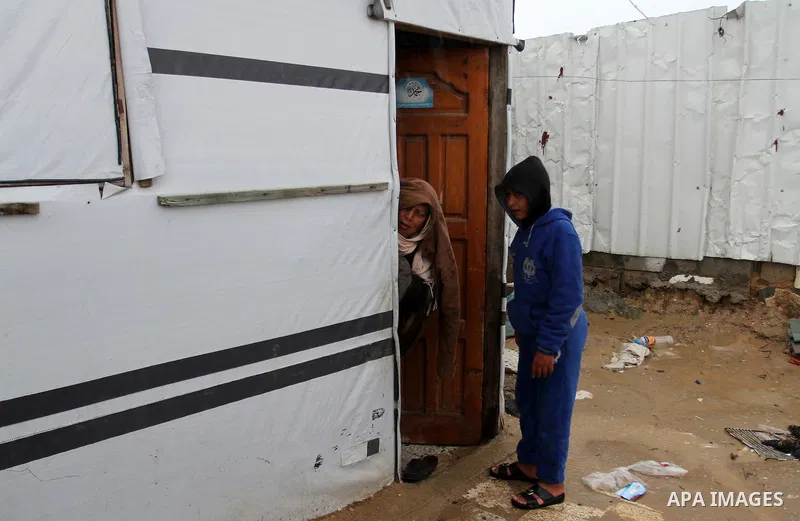 A Palestinian woman peaks from inside her temporary housing during a winter storm in the southern Gaza Strip town of Khan Younis on January 25, 2016. Photo by Abed Rahim Khatib