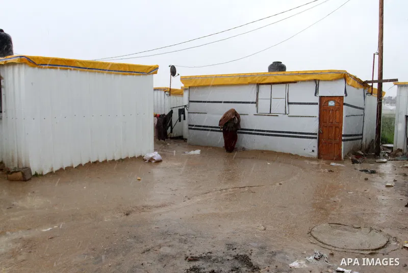 A Palestinian woman walks past temporary housing during a winter storm in the southern Gaza Strip town of Khan Younis on January 25, 2016. Photo by Abed Rahim Khatib