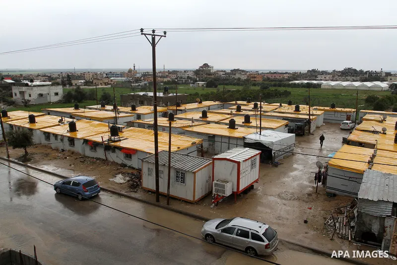 Cars drive into a flooded street next to temporary housing during a winter storm in the southern Gaza Strip town of Khan Younis on January 25, 2016. Photo by Abed Rahim Khatib