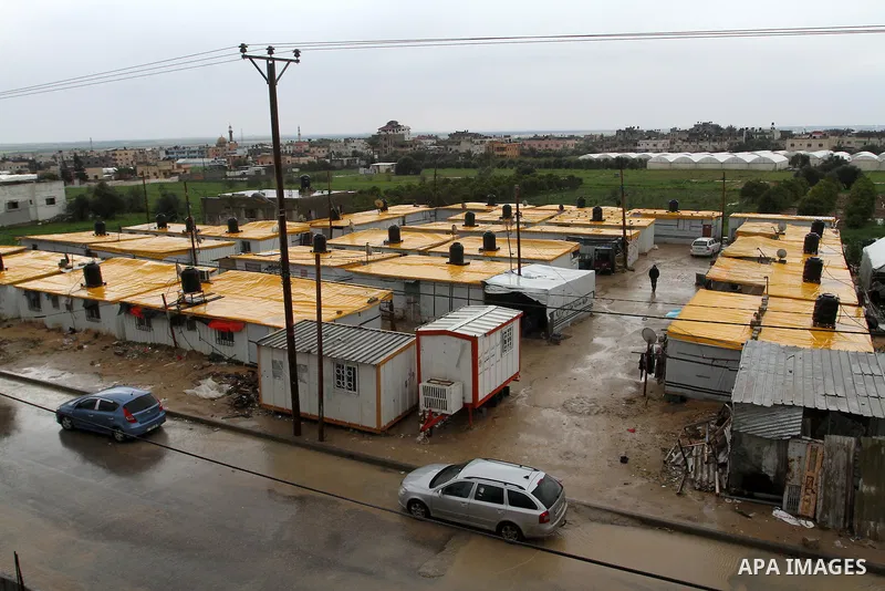 Cars drive into a flooded street next to temporary housing during a winter storm in the southern Gaza Strip town of Khan Younis on January 25, 2016. Photo by Abed Rahim Khatib