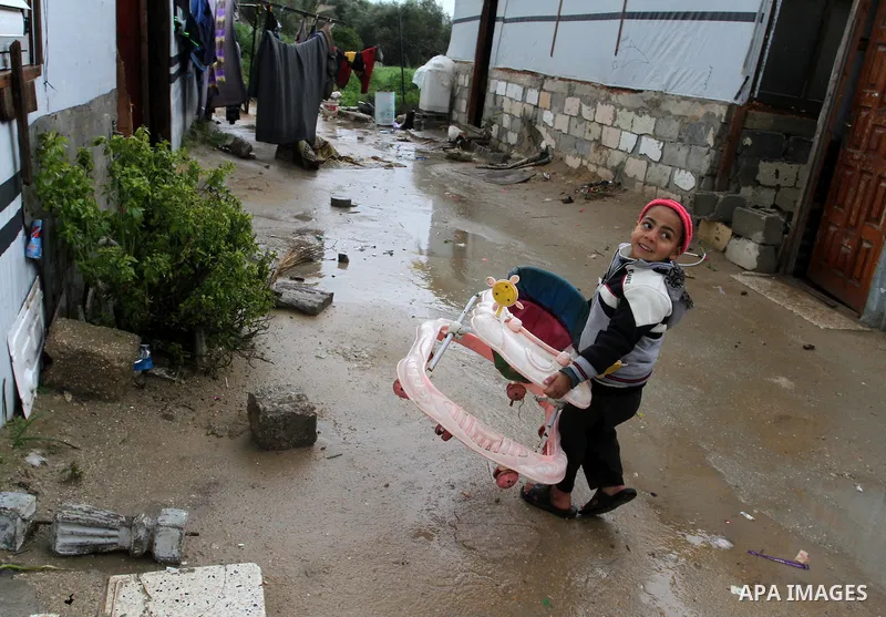 A Palestinian child walks past temporary housing during a winter storm in the southern Gaza Strip town of Khan Younis on January 25, 2016. Photo by Abed Rahim Khatib