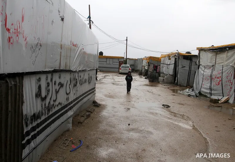 A Palestinian child walks past temporary housing during a winter storm in the southern Gaza Strip town of Khan Younis on January 25, 2016. Photo by Abed Rahim Khatib