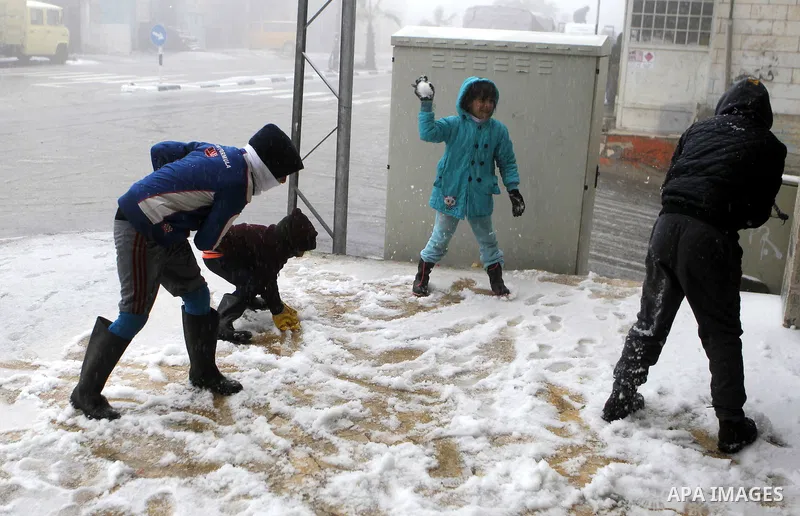 Palestinian children enjoy playing with the snow in the West Bank village of Halhul, near Hebron, during a snow storm on Jan. 25, 2016. Photo by Wisam Hashlamoun