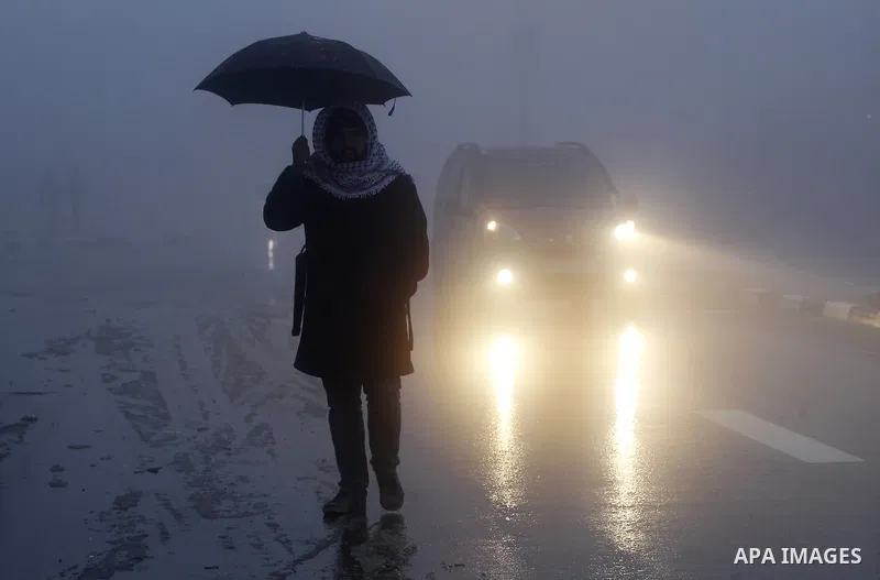 A Palestinian man holds umprella as he walks at a street during a snow storm in the West Bank village of Halhul, near Hebron, on Jan. 25, 2016. Photo by Wisam Hashlamoun