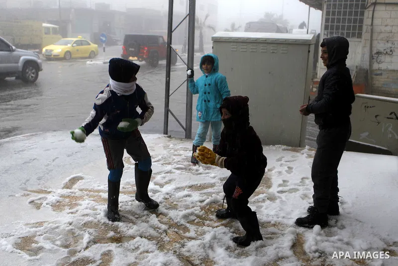 Palestinian children enjoy playing with the snow in the West Bank village of Halhul, near Hebron, during a snow storm on Jan. 25, 2016. Photo by Wisam Hashlamoun