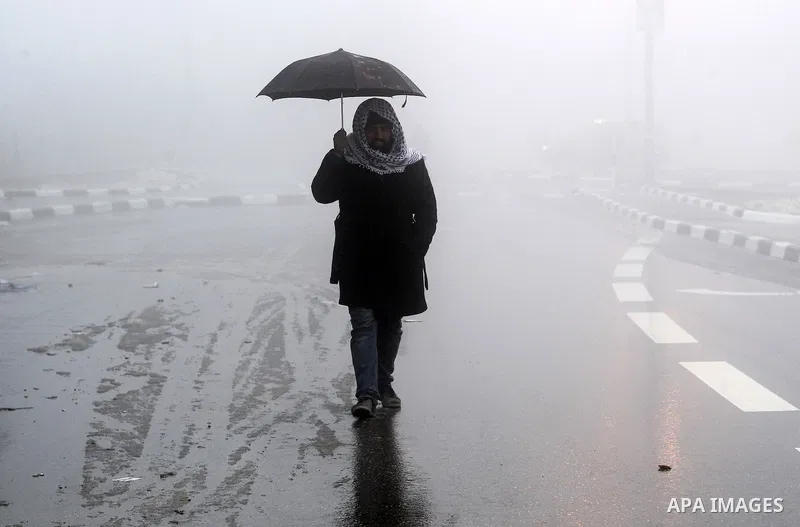 A Palestinian man holds umprella as he walks at a street during a snow storm in the West Bank village of Halhul, near Hebron, on Jan. 25, 2016. Photo by Wisam Hashlamoun