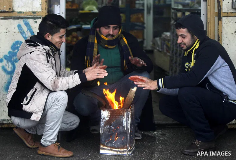 Palestinians warm themselves next to a fire during a snow storm in the West Bank village of Halhul, near Hebron, on Jan. 25, 2016. Photo by Wisam Hashlamoun