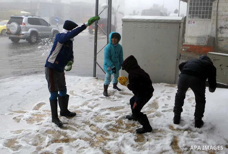 Palestinian children enjoy playing with the snow in the West Bank village of Halhul, near Hebron, during a snow storm on Jan. 25, 2016. Photo by Wisam Hashlamoun