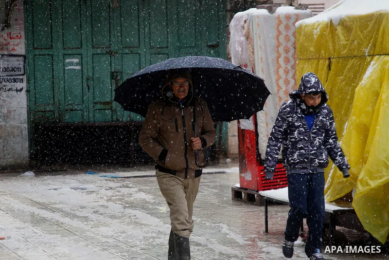 Palestinians walk during a snowstorm in the West Bank city of Hebron, on January 26, 2016. Photo by Wisam Hashlamoun