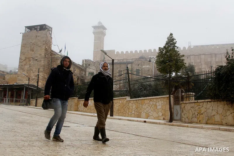 Palestinians walk during a snowstorm in the West Bank city of Hebron, on January 26, 2016. Photo by Wisam Hashlamoun