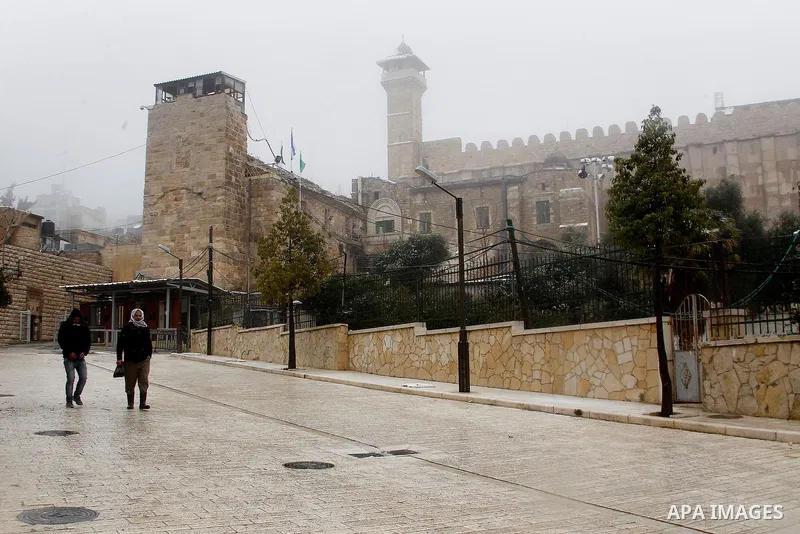 Palestinians walk during a snowstorm in the West Bank city of Hebron, on January 26, 2016. Photo by Wisam Hashlamoun