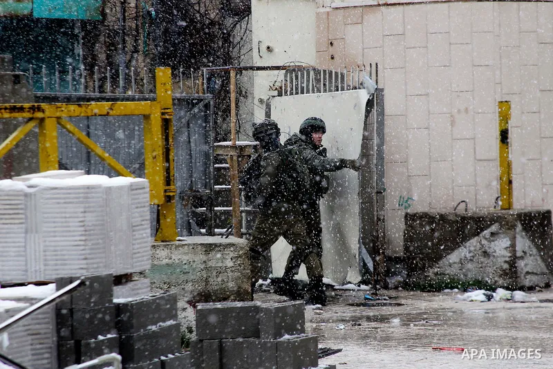 Israeli soldiers forces stand guard despite of the snow during a snowstorm in the West Bank city of Hebron, on January 26, 2016. Photo by Wisam Hashlamoun
