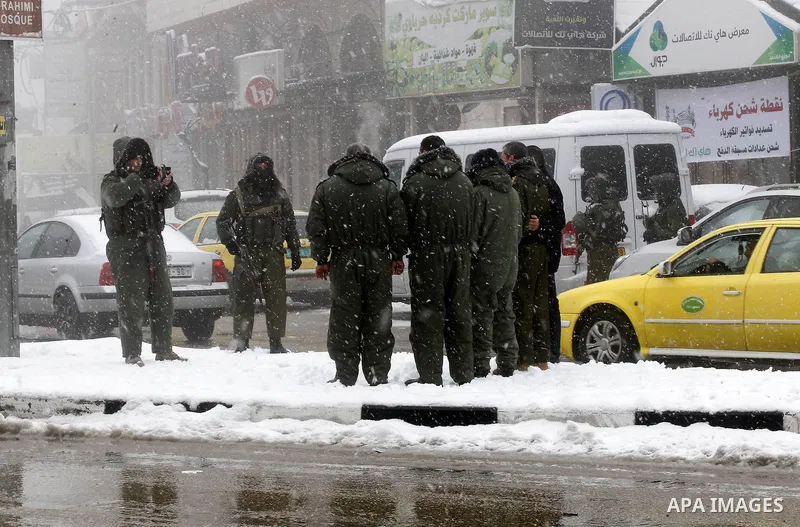 Palestinian National Security stand as they help citizens during a snowstorm in the West Bank city of Hebron, on January 26, 2016. Photo by Wisam Hashlamoun