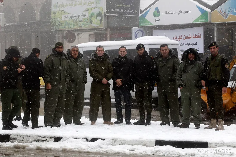 Palestinian National Security stand as they help citizens during a snowstorm in the West Bank city of Hebron, on January 26, 2016. Photo by Wisam Hashlamoun