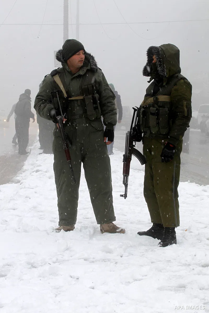 Palestinian National Security stand as they help citizens during a snowstorm in the West Bank city of Hebron, on January 26, 2016. Photo by Wisam Hashlamoun