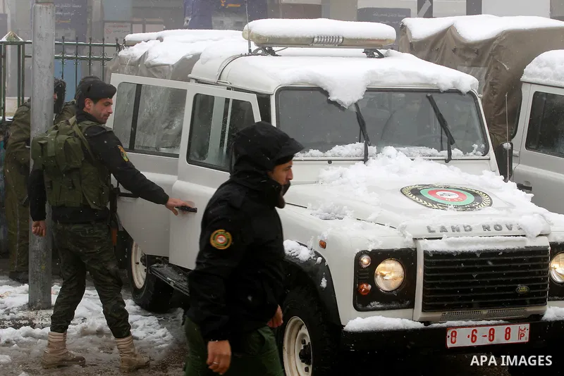 Palestinian National Security stand as they help citizens during a snowstorm in the West Bank city of Hebron, on January 26, 2016. Photo by Wisam Hashlamoun