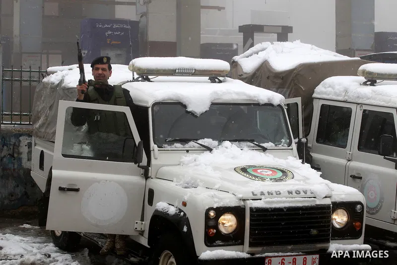 Palestinian National Security stand as they help citizens during a snowstorm in the West Bank city of Hebron, on January 26, 2016. Photo by Wisam Hashlamoun
