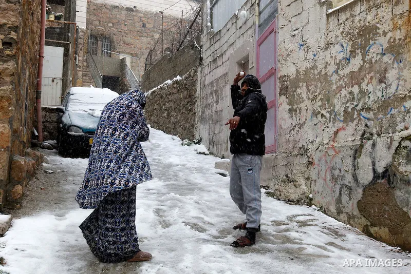 A Palestinian man plays with snow during a snowstorm in the West Bank city of Hebron, on January 26, 2016. Photo by Wisam Hashlamoun
