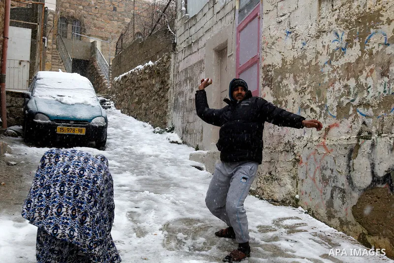 A Palestinian man plays with snow during a snowstorm in the West Bank city of Hebron, on January 26, 2016. Photo by Wisam Hashlamoun