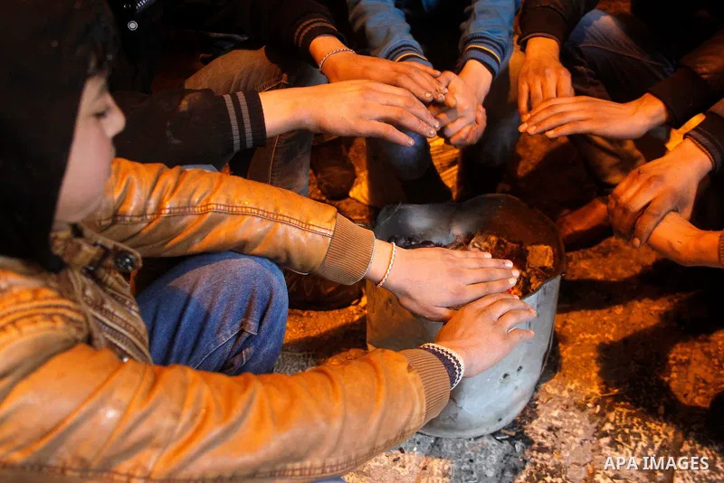 Palestinians warm themselves around a fire during a heavy winter storm in the West Bank city of Hebron, on January 26, 2016. Photo by Wisam Hashlamoun