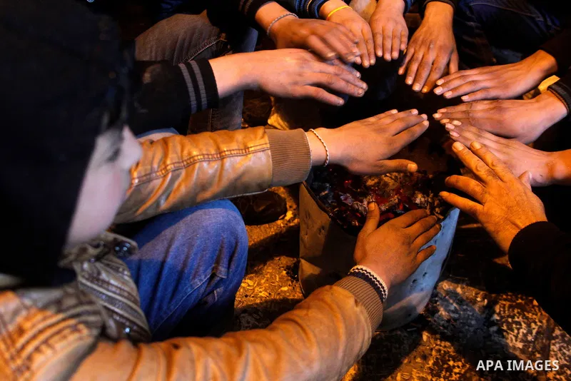 Palestinians warm themselves around a fire during a heavy winter storm in the West Bank city of Hebron, on January 26, 2016. Photo by Wisam Hashlamoun
