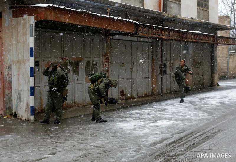Israeli security forces play with snow during a snowstorm in the West Bank city of Hebron, on January 26, 2016. Photo by Wisam Hashlamoun