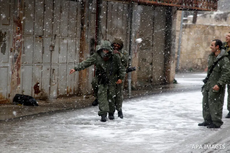 Israeli security forces play with snow during a snowstorm in the West Bank city of Hebron, on January 26, 2016. Photo by Wisam Hashlamoun