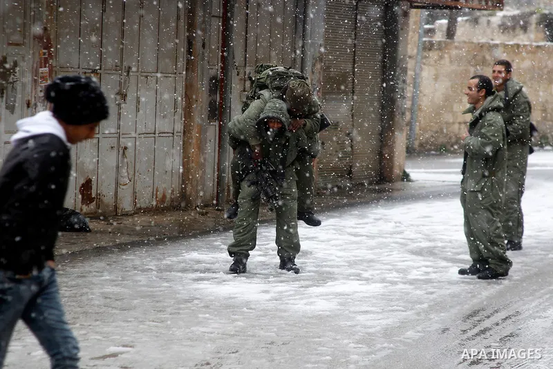 Israeli security forces play with snow during a snowstorm in the West Bank city of Hebron, on January 26, 2016. Photo by Wisam Hashlamoun