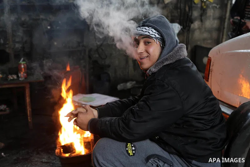 A Palestinian youth warms himself next to a fire during a winter storm in Gaza city on Jan. 26, 2016. Photo by Mohammed Asad