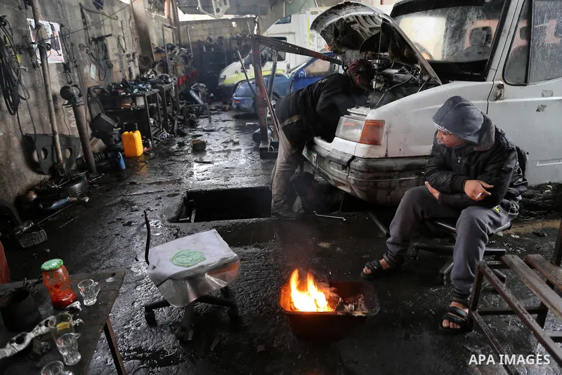 A Palestinian youth warms himself next to a fire during a winter storm in Gaza city on Jan. 26, 2016. Photo by Mohammed Asad
