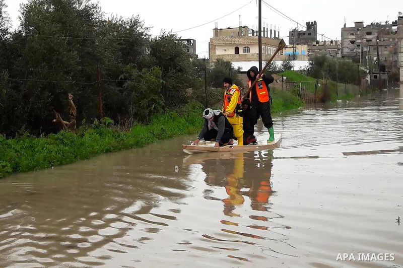Palestinian Civil Defence workers use a stand-up kayak to evacuate people from a flooded area following heavy rainfall in the southern Gaza Strip town of Rafah on January 26, 2016. Photo by Abed Rahim Khatib