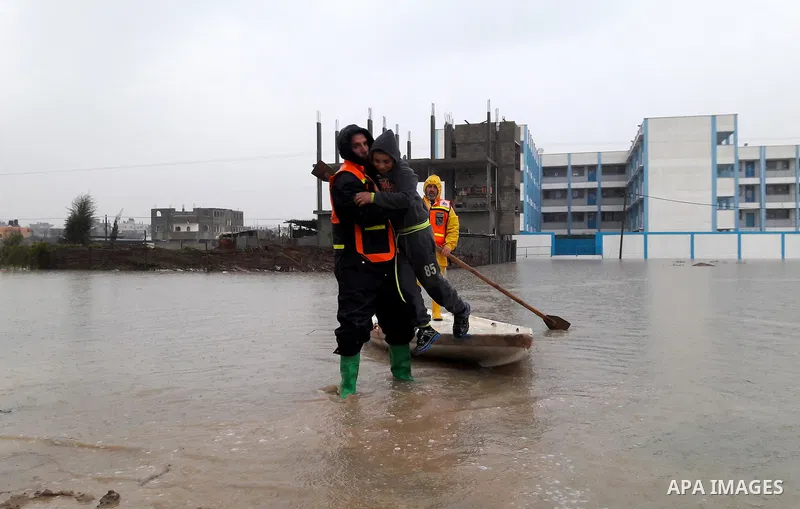 Palestinian Civil Defence workers use a stand-up kayak to evacuate people from a flooded area following heavy rainfall in the southern Gaza Strip town of Rafah on January 26, 2016. Photo by Abed Rahim Khatib